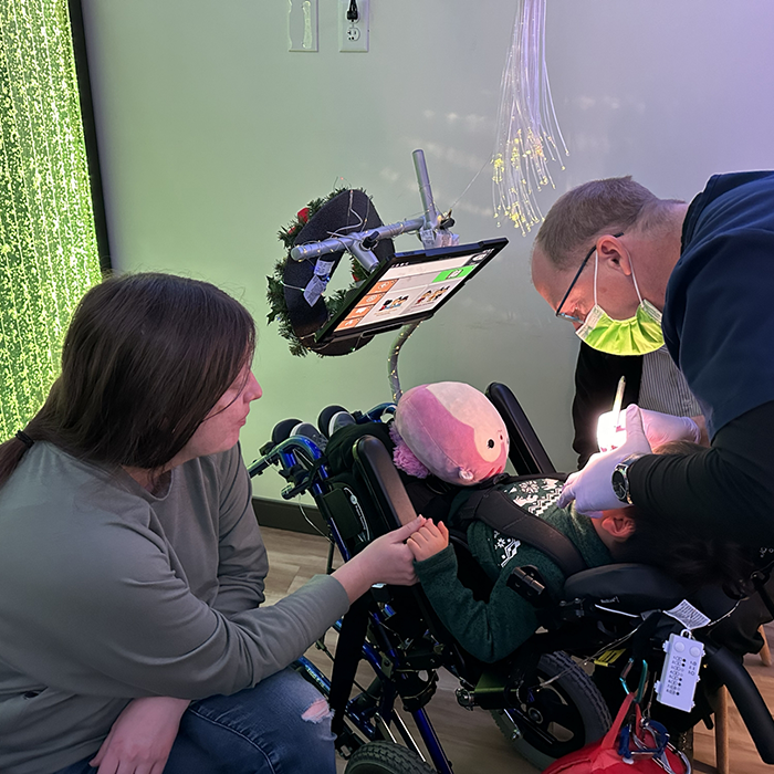 Doctor Patrick and a dental assistant treating a child in a wheelchair