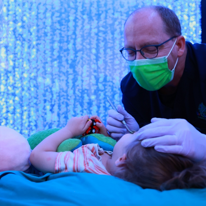Doctor Patrick smiling while he treats a baby patient